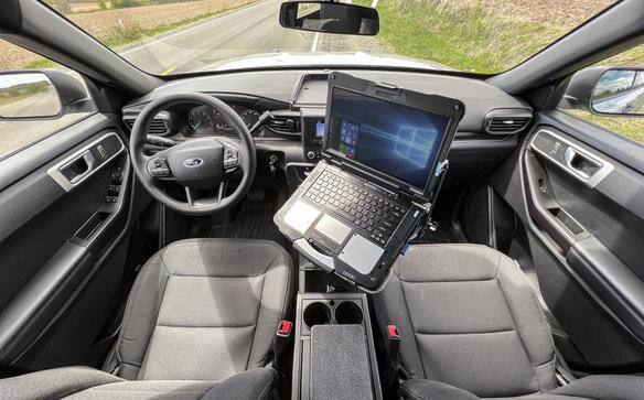 Laptop mounted on a stand inside a car's front cabin.