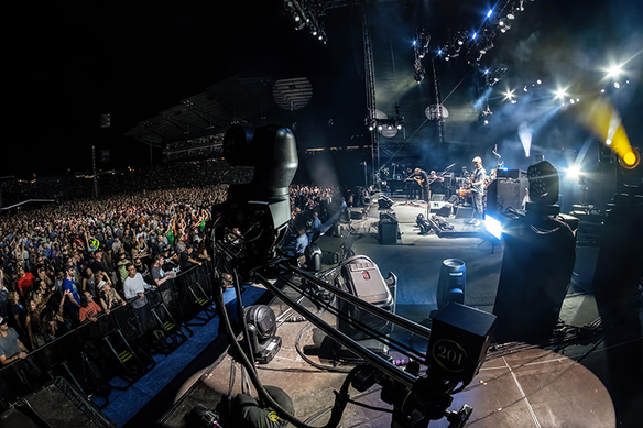 View of crowd inside theater from left hand stage while band plays music.
