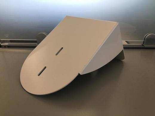 White wall mount bracket for PTZ cameras on a gray surface.