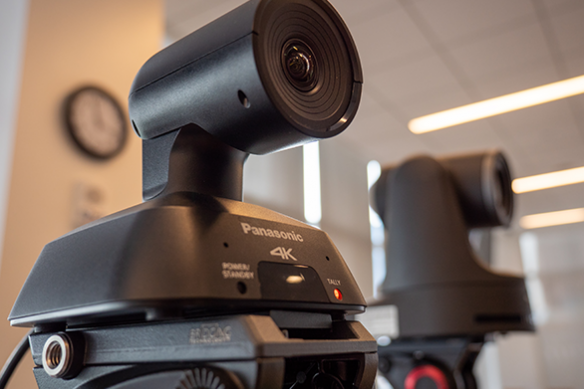 Close-up d'une caméra Panasonic 4K PTZ avec une autre caméra similaire floue en arrière-plan.