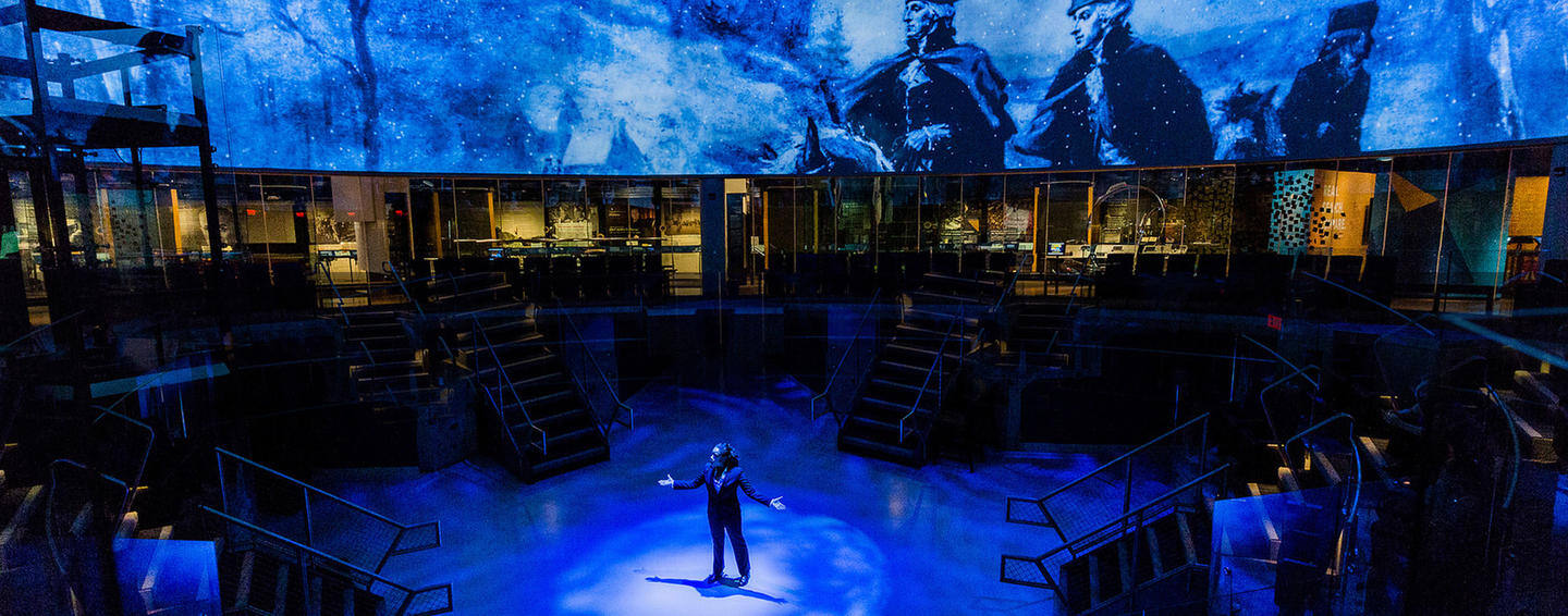 Person standing on stage surrounded by video walls