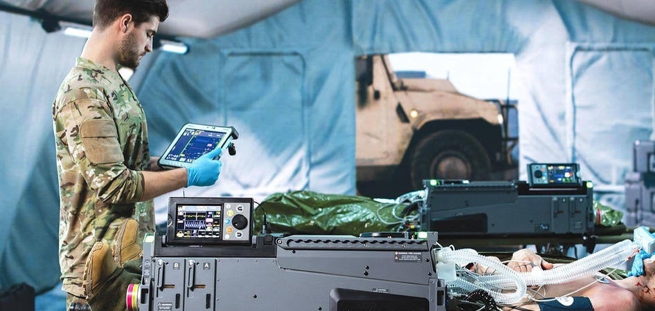 Personnel médical militaire dans une tente de triage avec une tablette TOUGHBOOK de Panasonic dans les mains