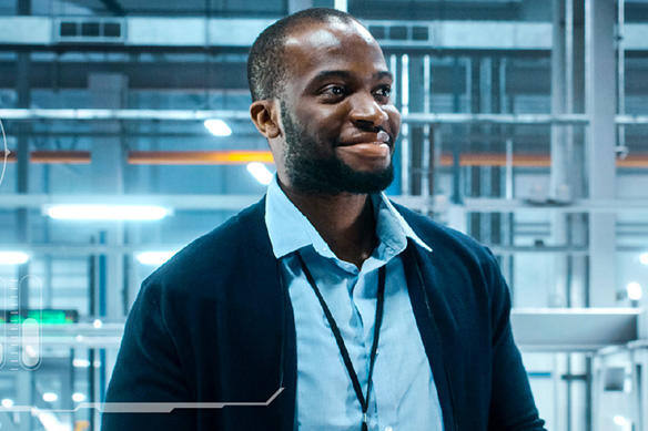 Man with blue collared shirt and navy blue cardigan smiling.