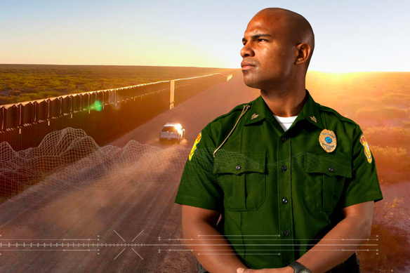 Man in uniform posing by crossing arms and looking to the left while a car drives down a dirt road on the background.