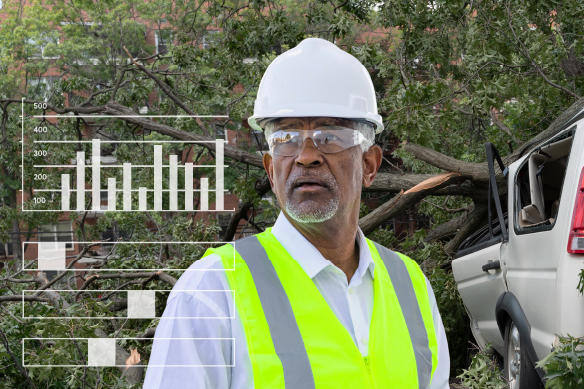 Man with safety hat, goggles, and vest looking towards camera while a crashed van is in the background