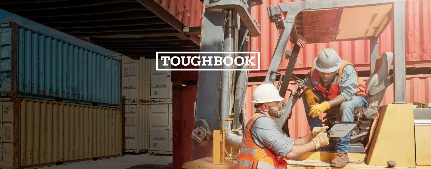 One construction worker showing and pointing at a tablet to another construction worker on a forklift